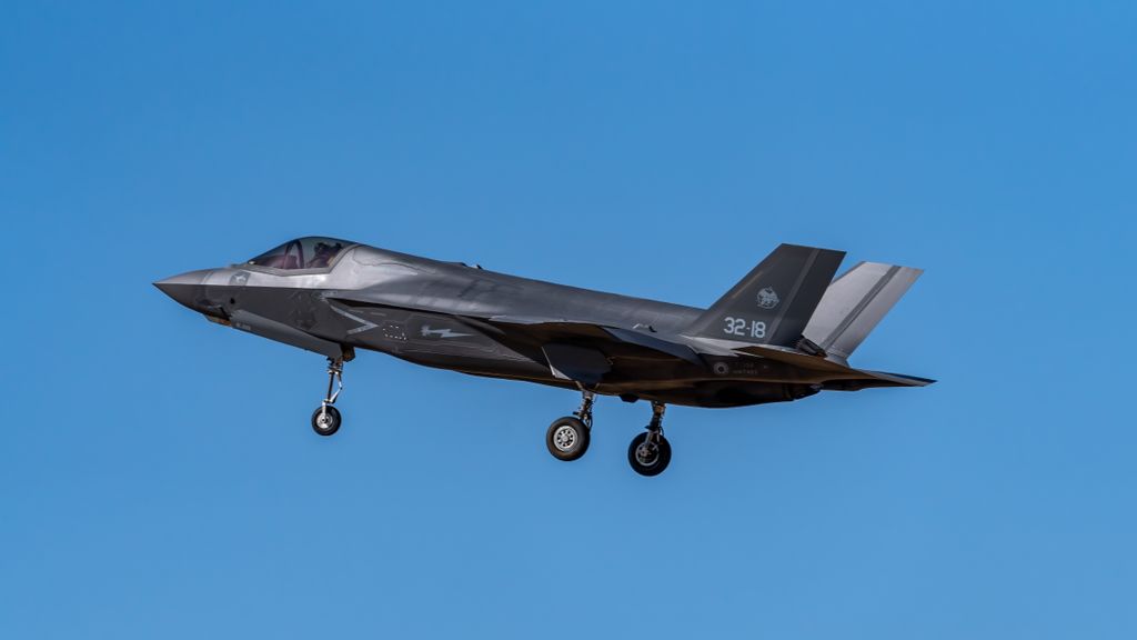 F-35 fighter jet soaring over Los Llanos, Spain, against a clear blue sky.